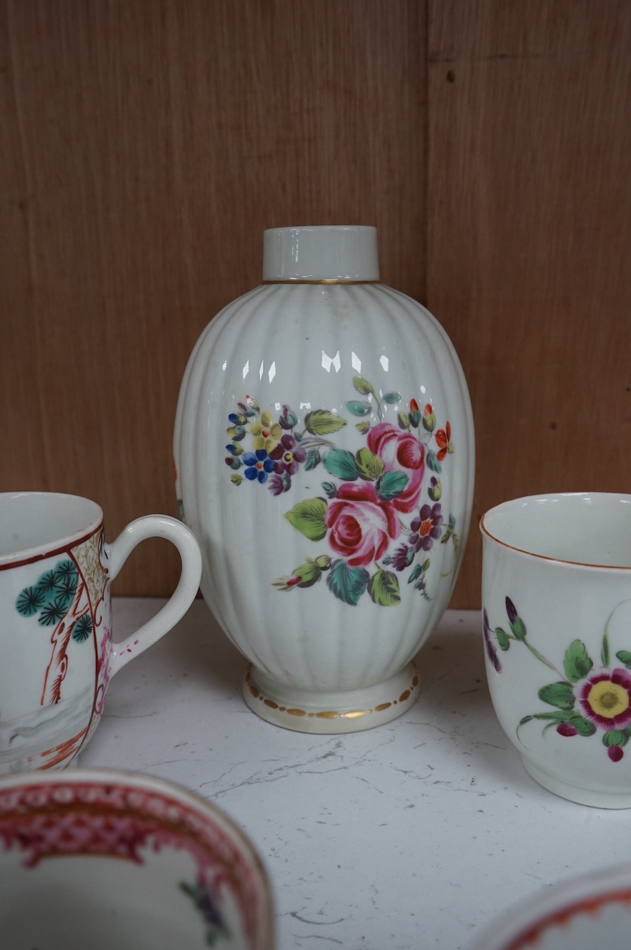 Worcester polychrome tea and coffee wares, c.1760-1780, comprising a tea caddy, a cream jug, five coffee cups and a fluted bowl, the latter with red anchor mark (8), largest tea caddy 14cm high.